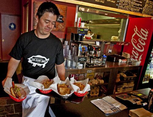 Owner Ray Byrne prepares to serve a few of his creations at his new Pasadena restaurant, the Slaw Dogs, which subjects America's humblest food to the free play of the imagination.