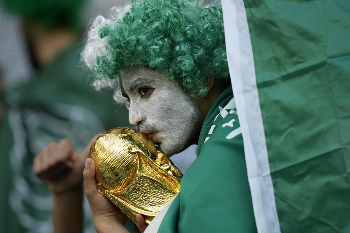 A Saudi Arabia fan kisses a copy of the World Cup trophy prior of the World Cup 