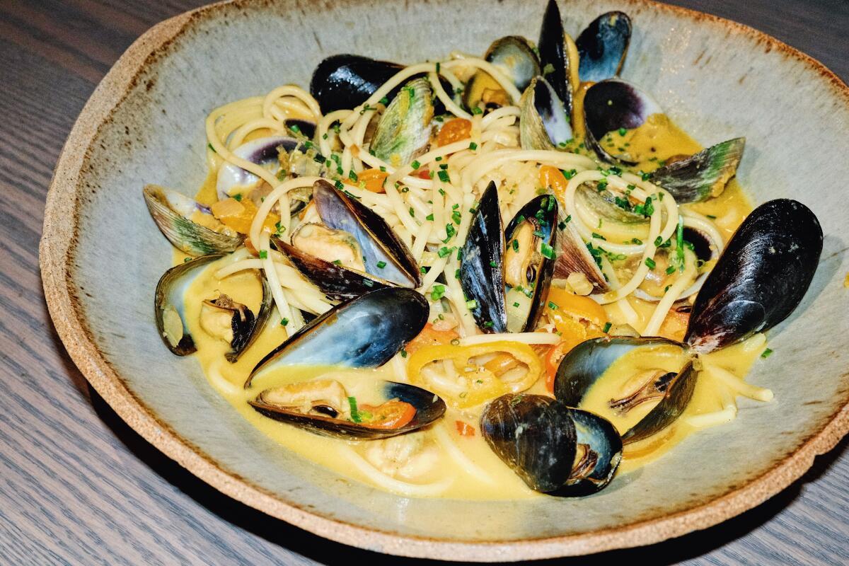 A bowl of spaghetti alla chitarra with mussels and clams in a yellow sauce