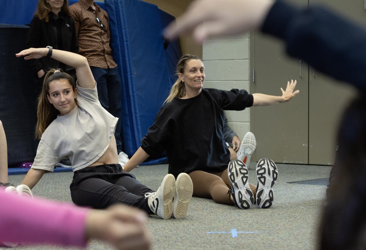 Newport Harbor's Emma Chaix, left, stretches before teaching a dance class at Bonita Creek Park.