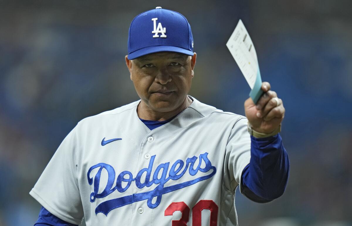 Dodgers manager Dave Roberts raises the lineup card in his left hand before a game.