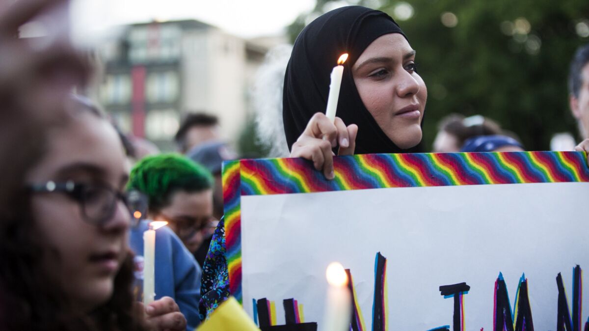A Muslim woman holds a candle and a sign that references the hashtag "#NotInMyName" to show that many in the Islamic faith support the LGBT community during a vigil in Seattle on June 12.