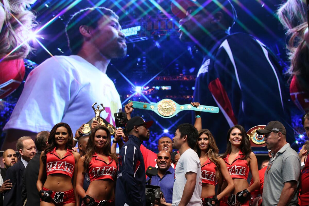 A big screen behind them shows Floyd Mayweather Jr. and Manny Pacquiao posing face to face after their weigh-in Friday.