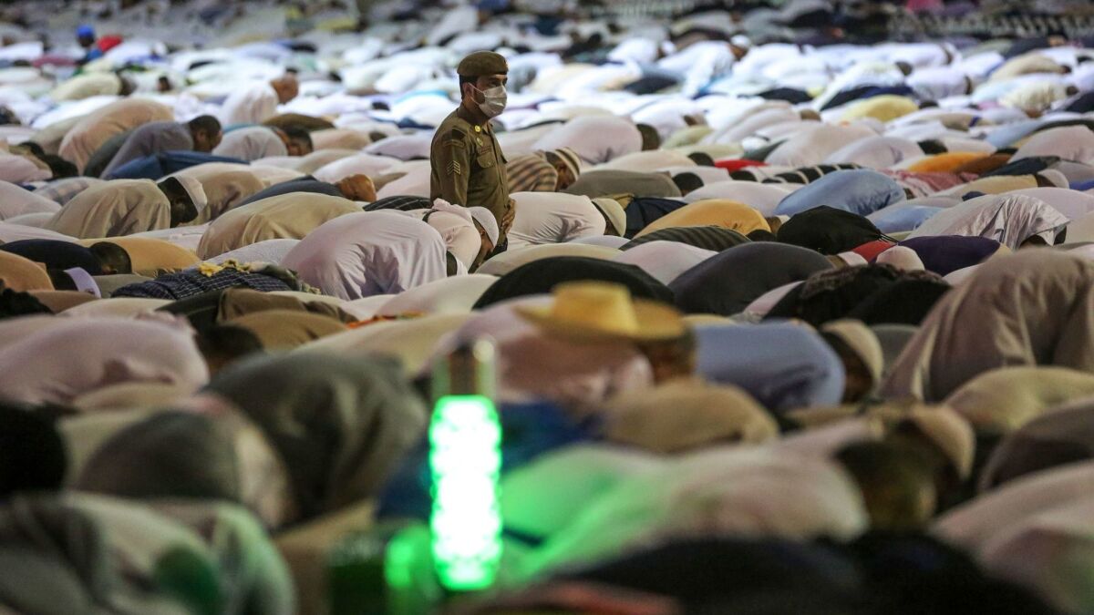 A Saudi security officer stands among Muslim worshipers as they perform prayers around the Kaaba.