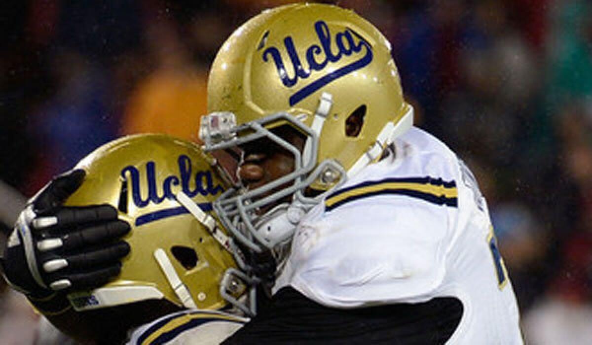 UCLA left tackle Simon Goines, right, shown hugging teammate Johnathan Franklin last November, injured his right knee Thursday during a scrimmage.