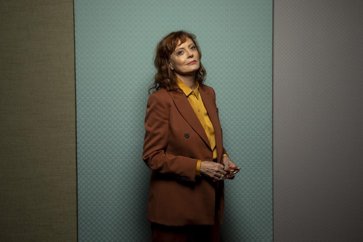 Actor Susan Sarandon stands against a green background for a photo.
