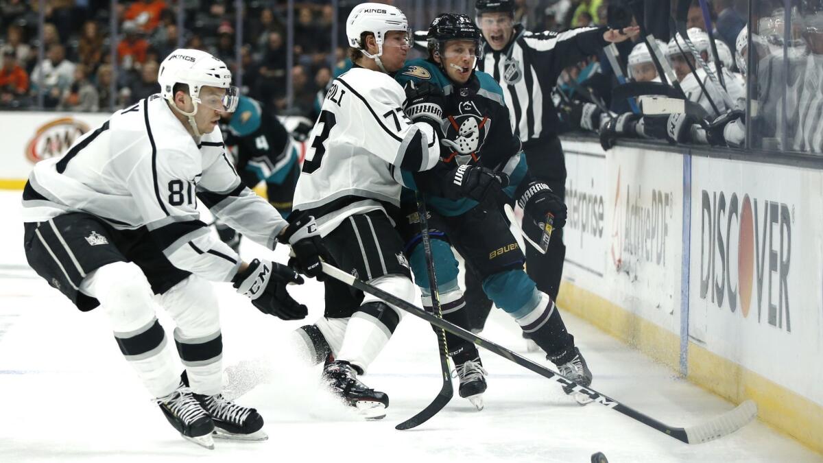 The Kings' Tyler Toffoli, center, and the Ducks' Rickard Rakell fight for control of the puck as L.A.'s Matt Roy moves in during a March 10 game at Honda Center.