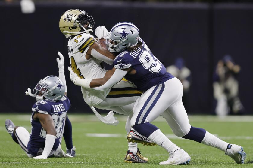 New Orleans Saints wide receiver Kawaan Baker (14) is hit by Dallas Cowboys defensive tackle Osa Odighizuwa (97) during the first half of an NFL football game, Thursday, Dec. 2, 2021, in New Orleans. (AP Photo/Brett Duke)