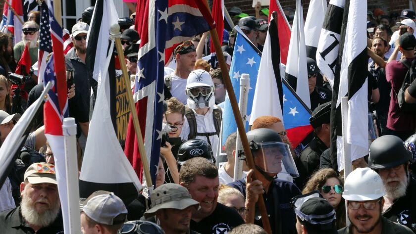 White nationalist demonstrators walk into the entrance of Lee Park surrounded by counter-demonstrators in Charlottesville, Va., last year.