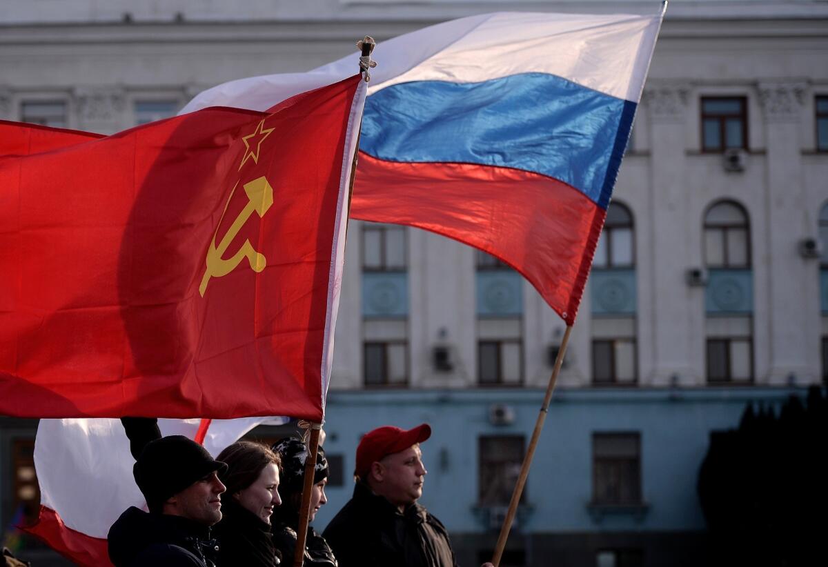 Men hold Russian (right) and Soviet Union flags in Simferopol's Lenin Square on Sunday. Polls opened in a referendum on the peninsula of Crimea, in which voters are to voice their wish to either join Russia or become an effectively independent state connected to Ukraine.