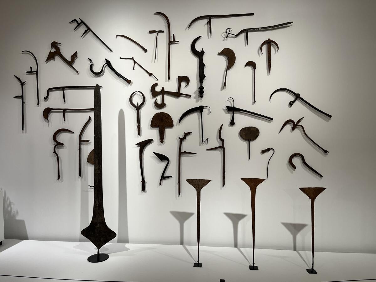 A gallery wall displays heavy tools crafted from iron that take an array of sharp and curving shapes