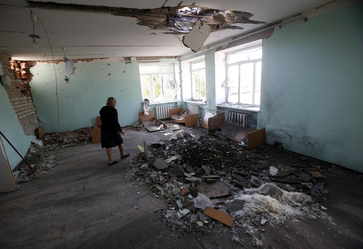 A teacher surveys the damage at her kindergarten from shelling in the village of Novosvitlivka, one of more than a dozen eastern Ukraine locales hit in a resurgence of artillery firing on Sunday and Monday.