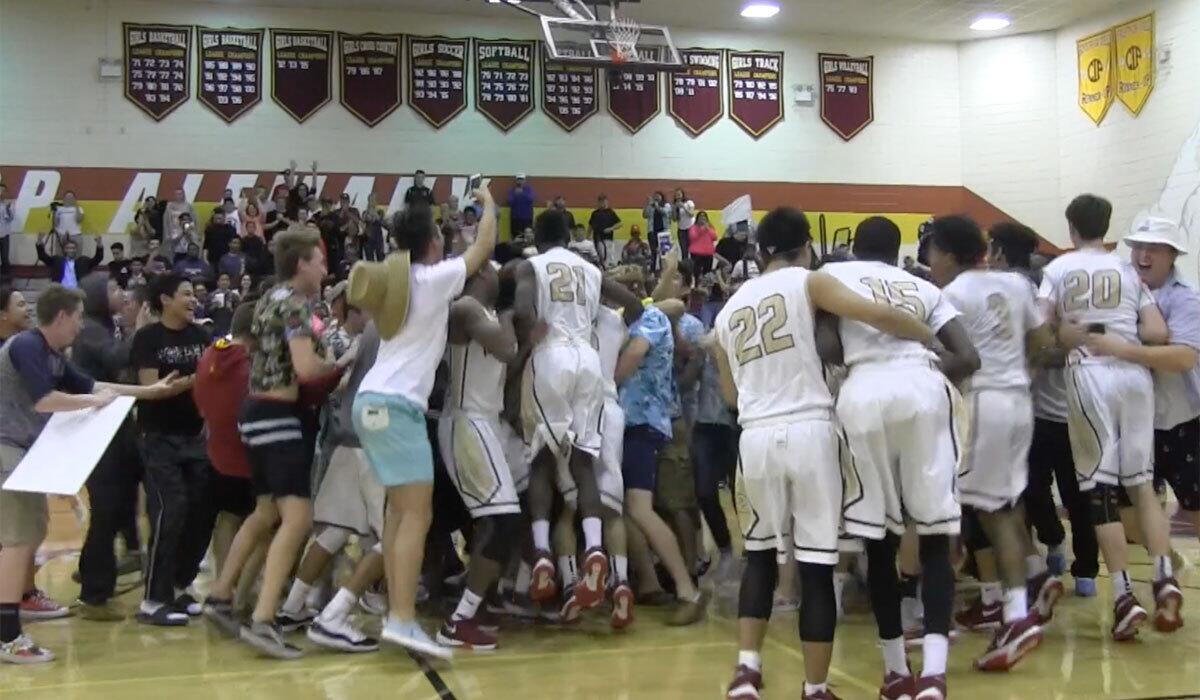 Alemany students charge onto court to celebrate basketball victory over Crespi on Monday night.