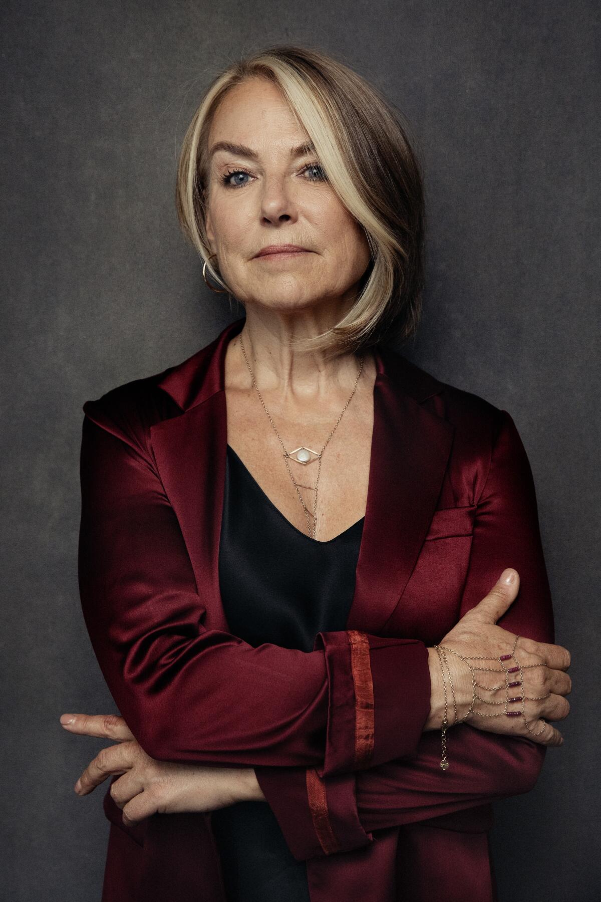 A woman in a maroon jacket crosses her arms 