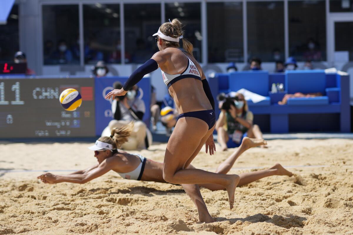 U.S. beach volleyball player Alix Klineman dives for a ball as teammate April Ross looks on.