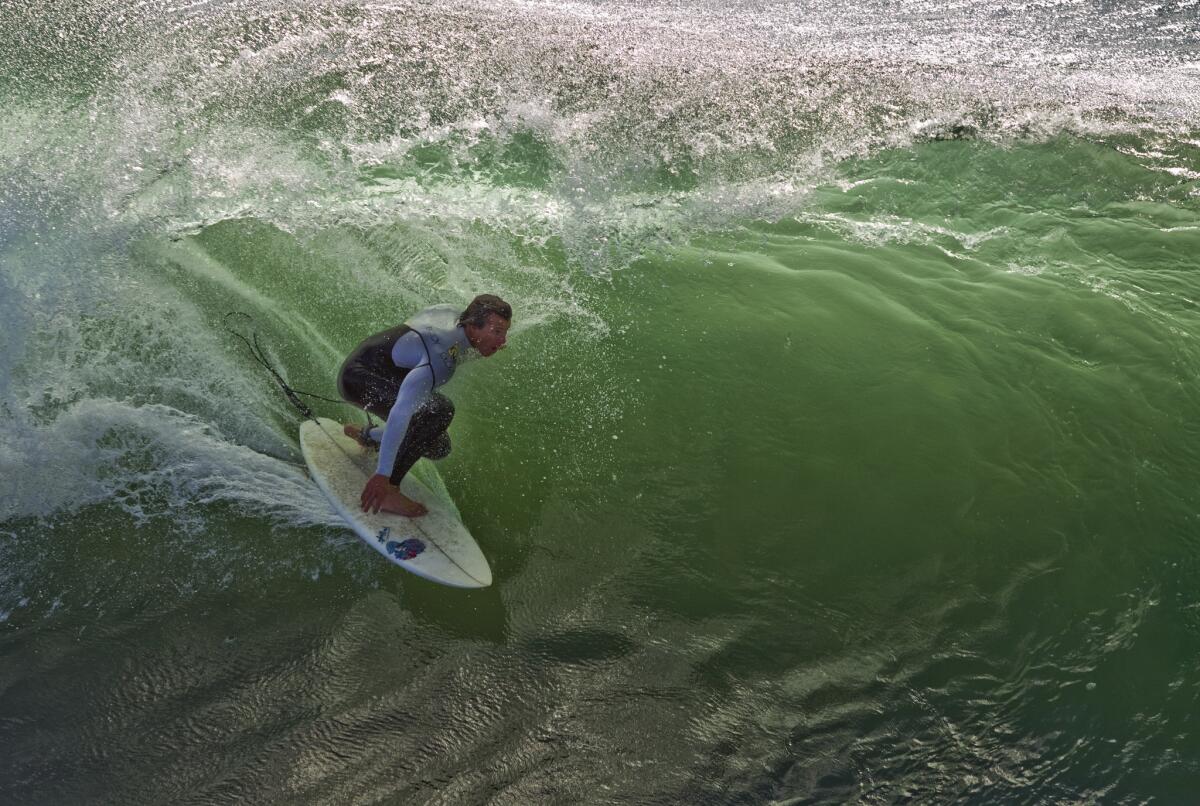 A surfer catches a wave in high surf at the Huntington Beach pier.