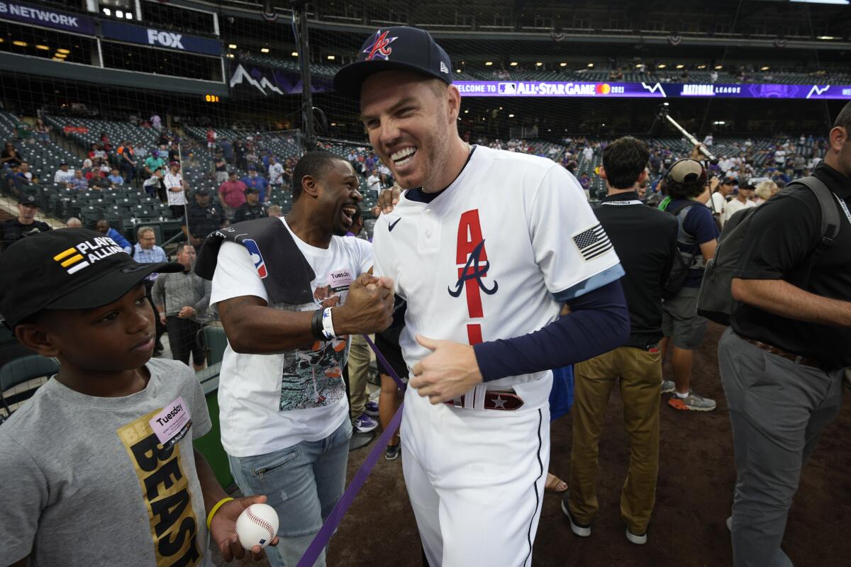 National League's Freddie Freeman, of the Atlanta Braves, laughs with former player Michael Bourn 