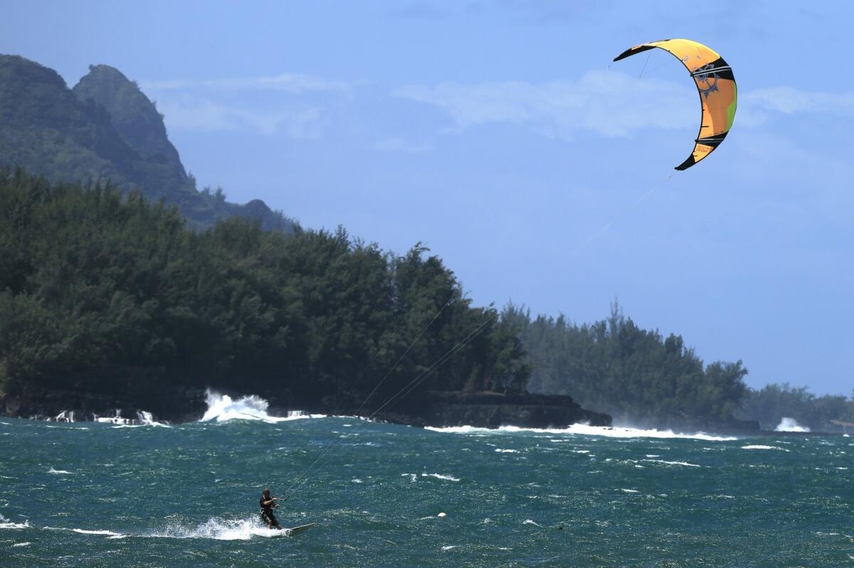 A kite surfer skims across Hanalei Bay's choppy waters.