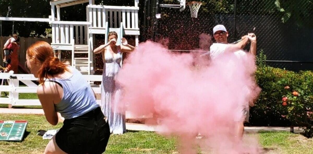 Matt Luderer hits a ball pitched by daughter Grace to reveal the identity of the next baby in the family.