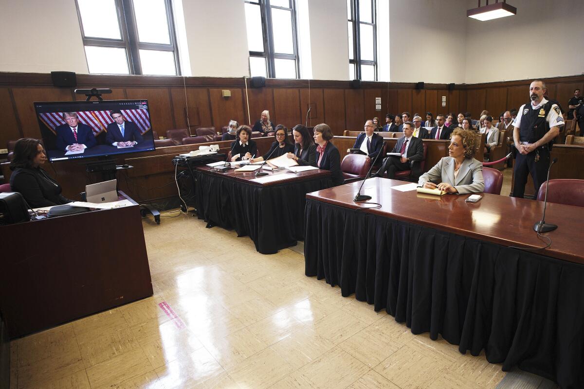 A courtroom scene with a video screen set up to one side