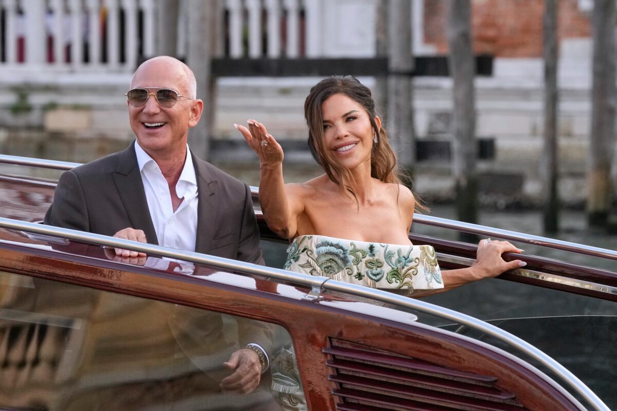 A man in sunglasses next to a woman waving.