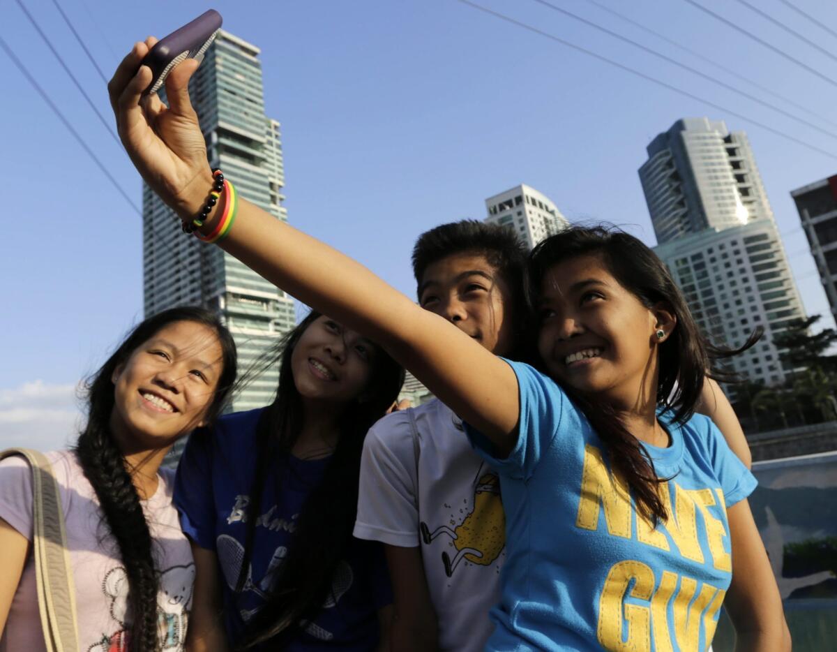 Filipino teens pose for a selfie group picture overlooking Makati City's skyline in the Philippines. The city has been dubbed the selfie capital of the world.