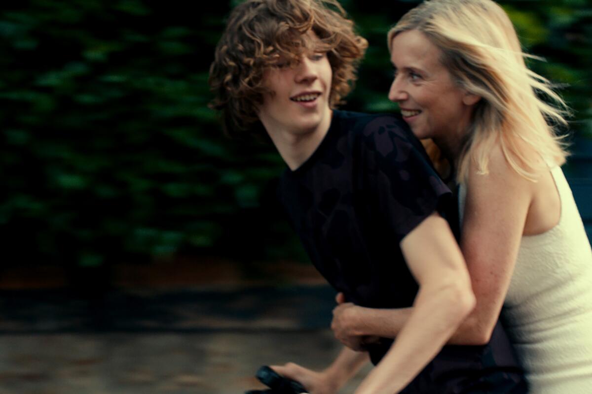 A young man rides a bike with an older woman clutching him from behind in a scene from Catherine Breillat's "Last Summer." 