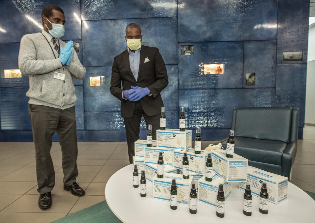 Thomas Uwal, left, Human Services Superintendent for the city of Inglewood, shows his appreciation after Dr. Bill Releford, right, founder of the Black Barbershop Health Outreach Program, donated 650 surgical masks and 100 bottles of hand sanitizer to the Inglewood Senior Center.