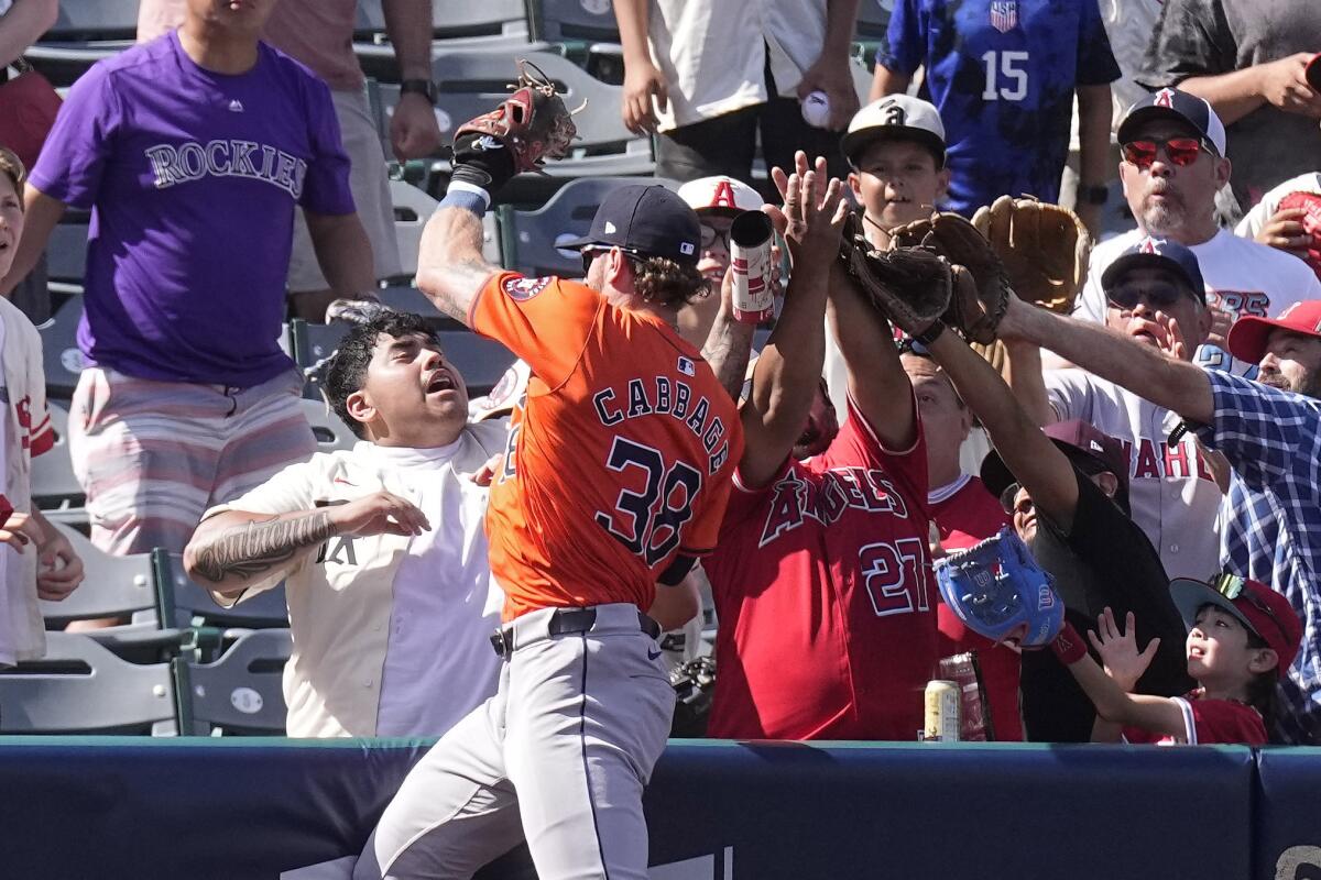 Houston Astros left fielder Trey Cabbage initially catches a ball hit by Angels catcher Logan O'Hoppe but drops it.