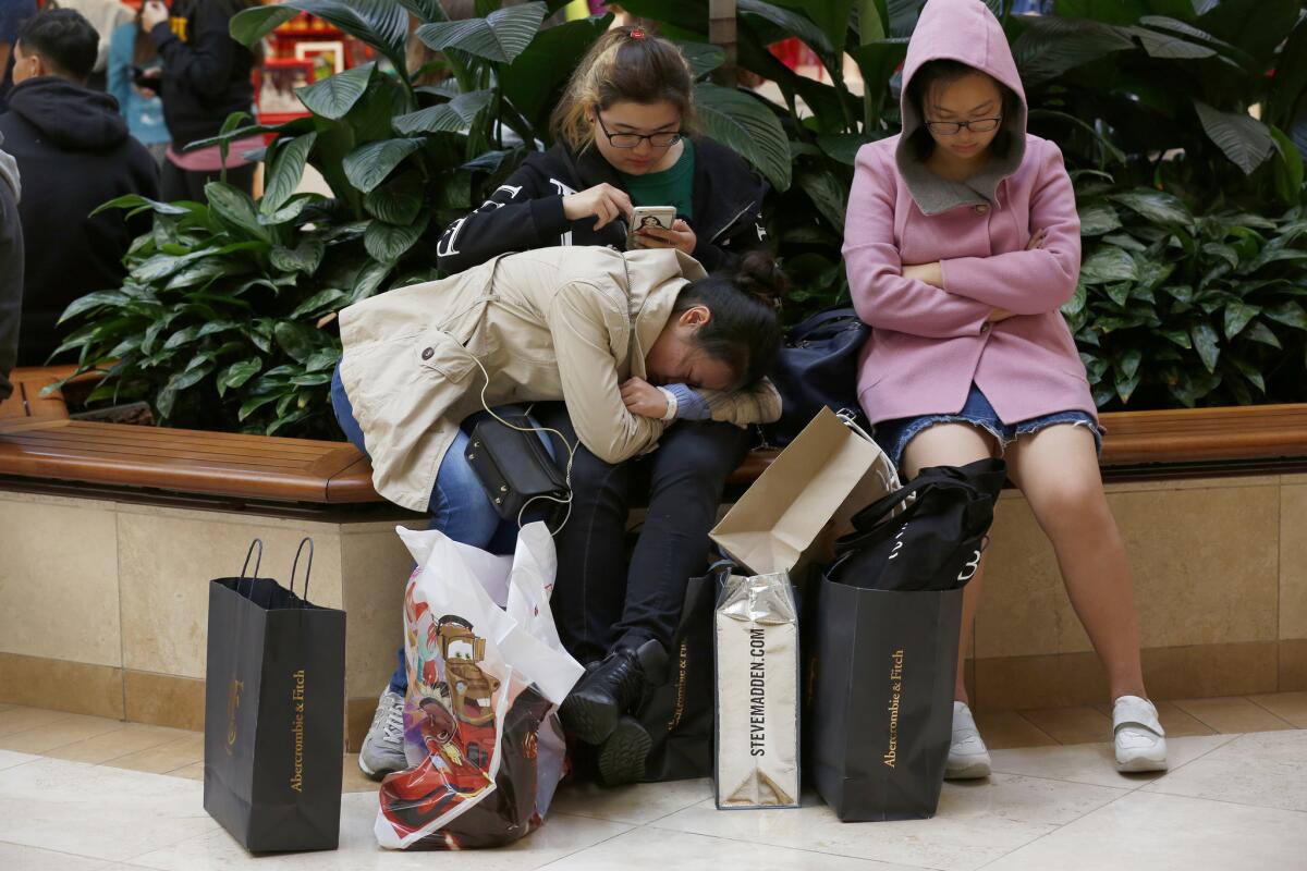 Tired shoppers in Costa Mesa's South Coast Plaza mall take a break on Black Friday.