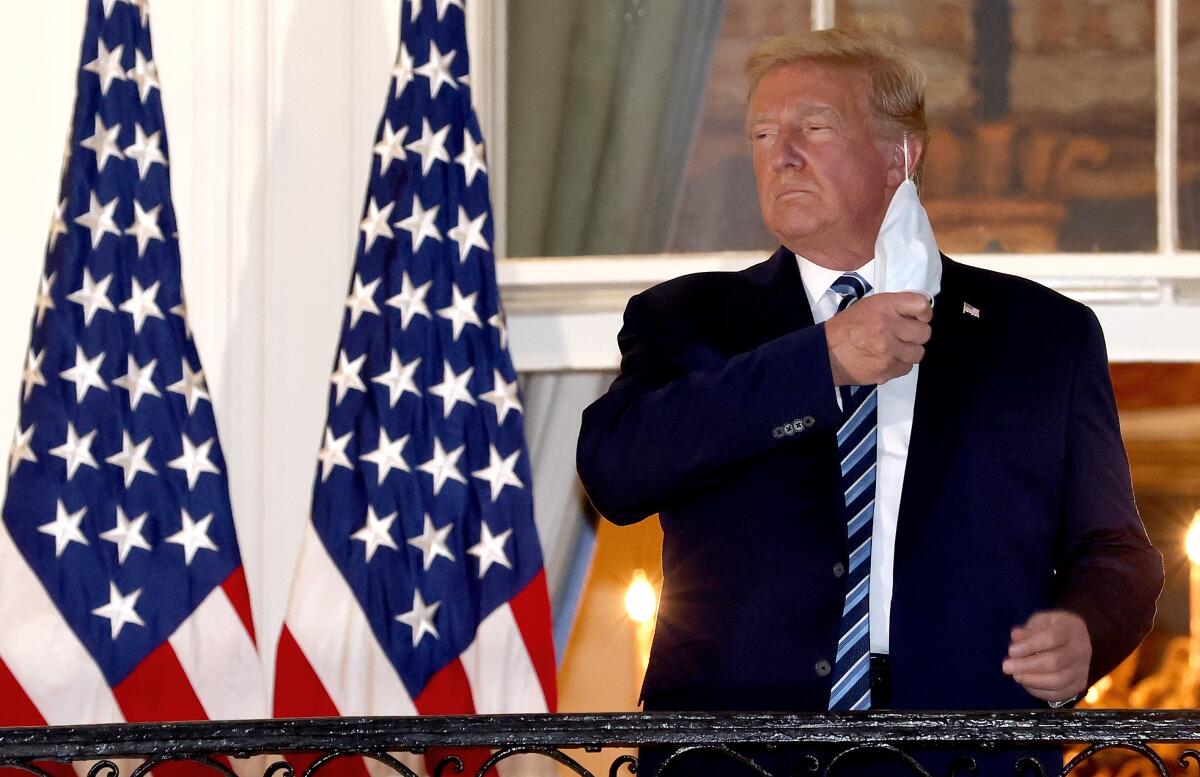 President Trump taking off his mask standing on a White House balcony after returning from the hospital.