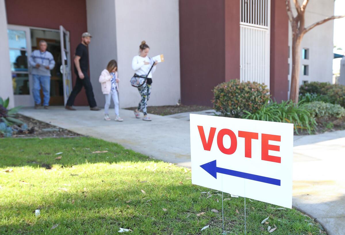 Katie VanBerckelaer, 43, and her daughter Viola, 7, leave the vote center at the Costa Mesa Senior Center on Tuesday after VanBerckelaer cast her ballot.