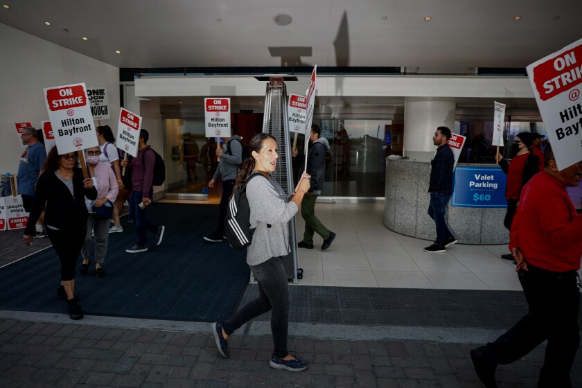 Hilton San Diego Bayfront workers picket while holding "On strike" signs 