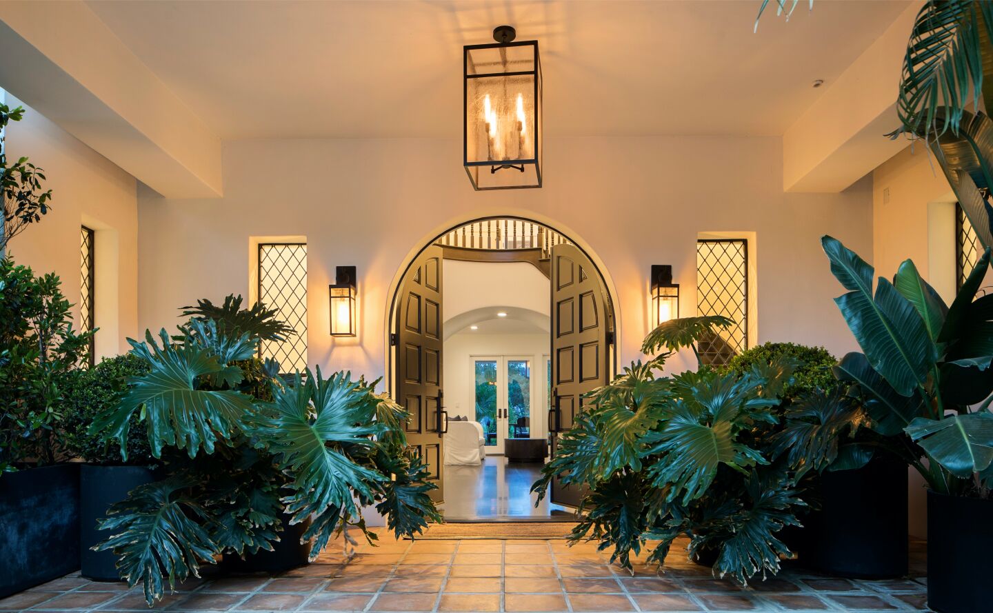 High-ceiling entry with archway, greenery and lighting.