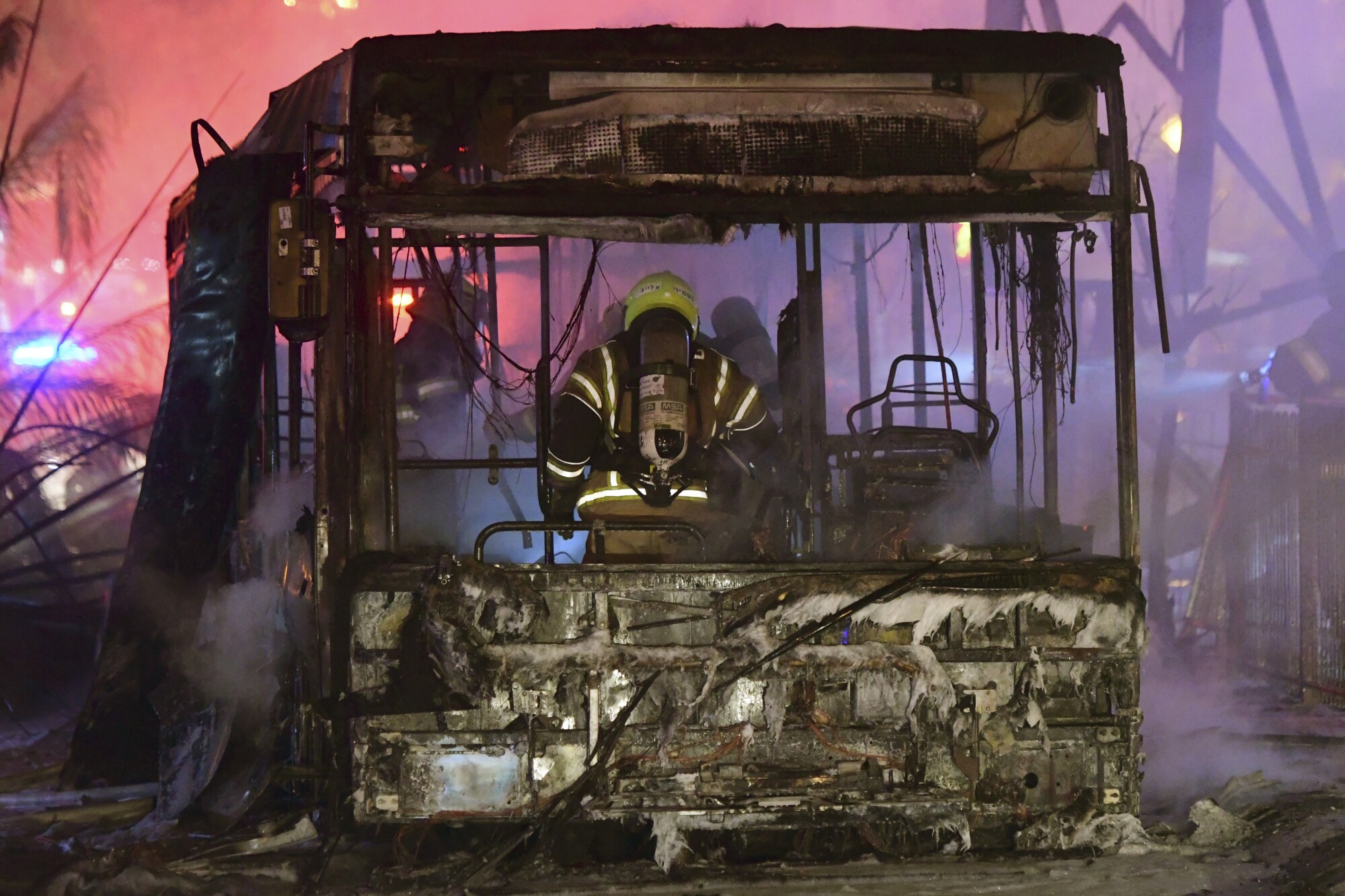 A firefighter stand in the scorched wreckage of a bus