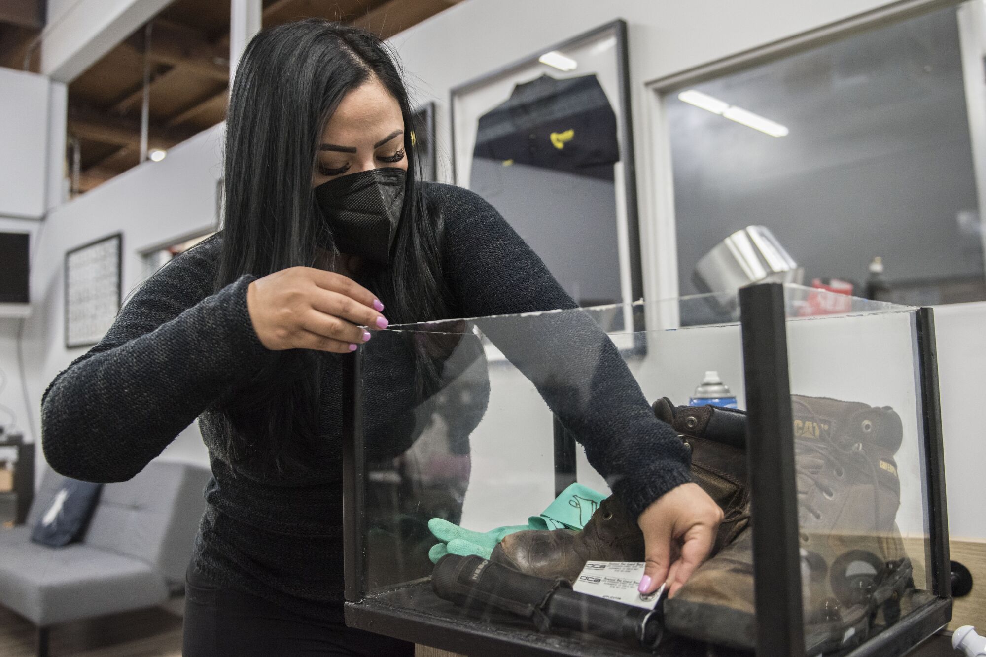Nidia Campos places her brother's work gear in a display case.