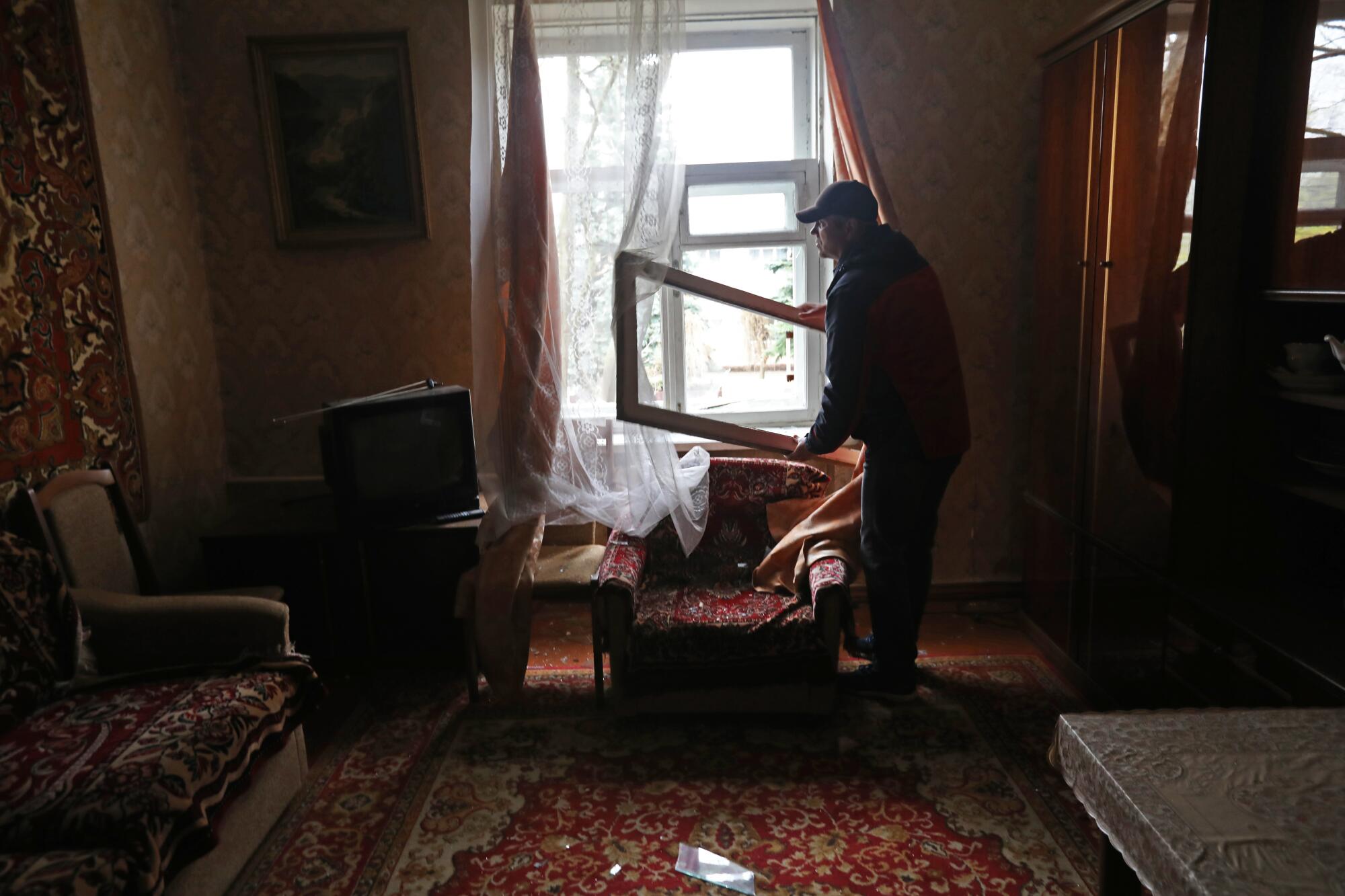 Alexy Dyakov removes the window frame after the windows were broken by a Russian missile attack in Kramatorsk, Ukraine