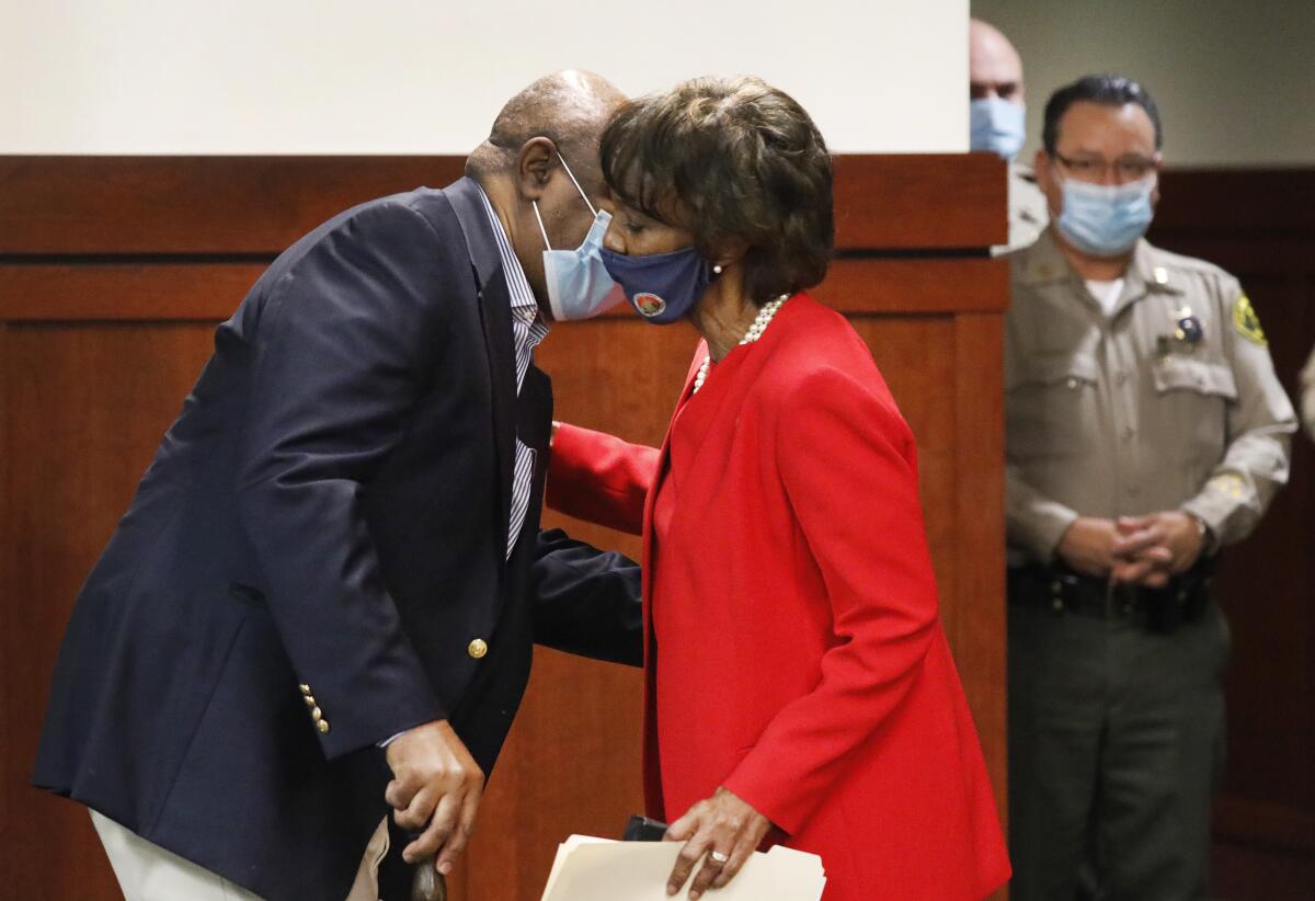 Los Angeles County Dist. Atty. Jackie Lacey kisses her husband, David, in a courtroom
