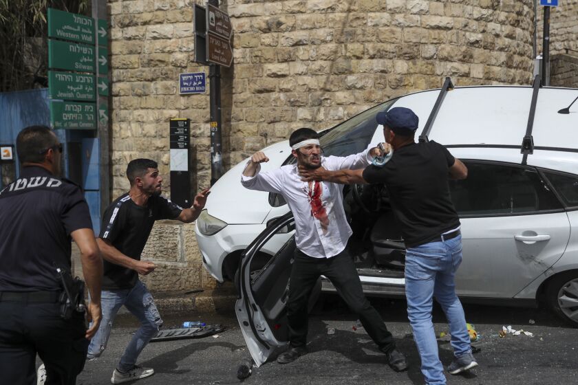 A Jewish driver, center, scuffles with Palestinians after he was attacked by Palestinian protesters near Jerusalem's Old City. Monday, May 10, 2021. Israeli police clashed with Palestinian protesters at a flashpoint Jerusalem holy site on Monday, the latest in a series of confrontations that is pushing the contested city to the brink of eruption. Palestinian medics said at least 200 Palestinians were hurt in the violence at the Al-Aqsa Mosque compound, including 150 who were hospitalized. (AP Photo/Ohad Zwigenberg)