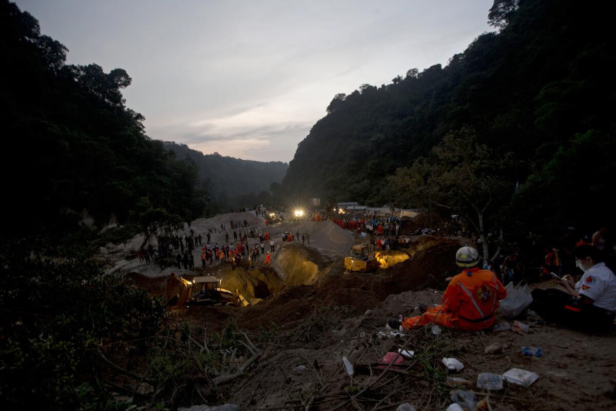 Rescue workers search for survivors at the the site of a landslide in Cambray, about 10 miles east of Guatemala City, on Oct. 2, 2015.