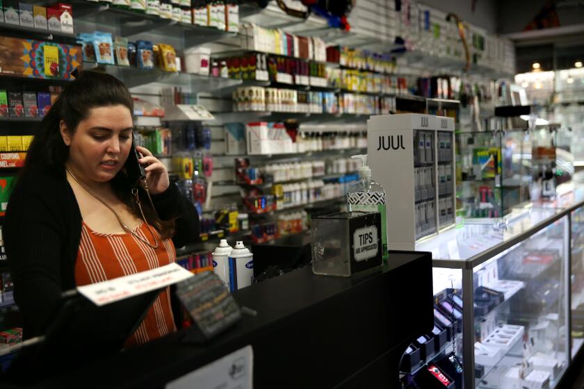 LOS ANGELES, CA - APRIL 16, 2020: Natali Mishali grabs a quick phone call while at DTLA Smoke Shop on April 16, 2020, in Los Angeles, California. In early April, Mishali's shop was one of the first four in the city of Los Angeles criminally charged for refusing to shut down during the quarantine as city officials deemed the smoke shop a non-essential business. Mishali claimed for weeks that her store should have been allowed to operate as an essential business since it sold dry goods, paper products and cleaning supplies. The city eventually confirmed to her that she was in violation of state law. ({Dania Maxwell} / {Los Angeles Times})
