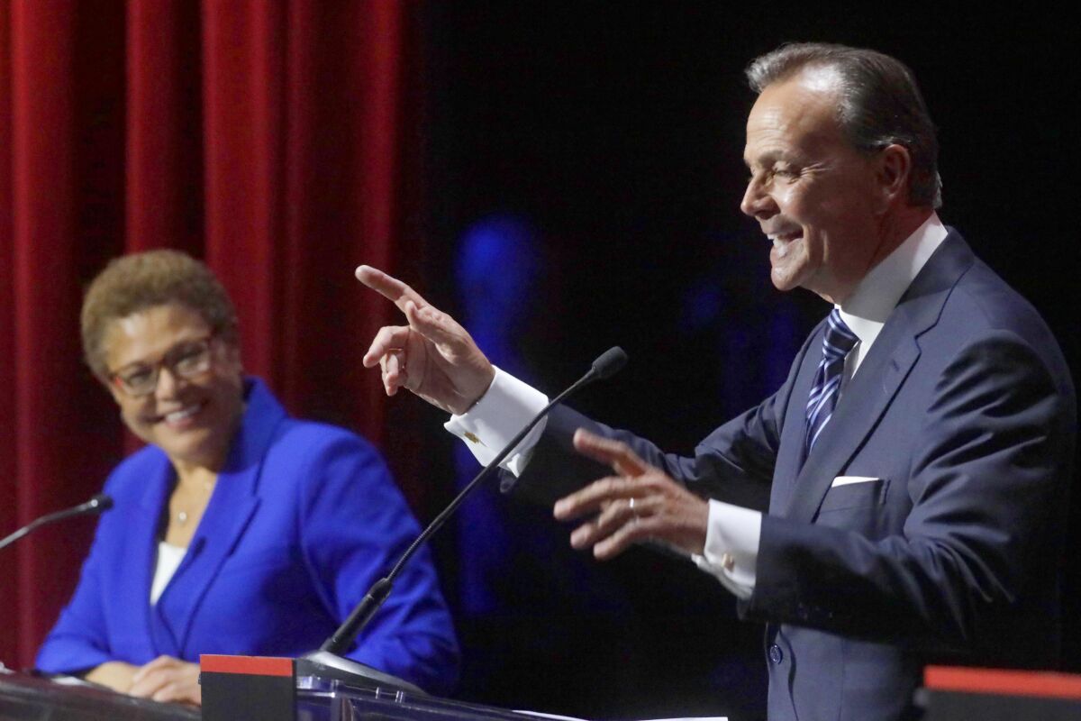 A man speaks at a microphone as a woman smiles.
