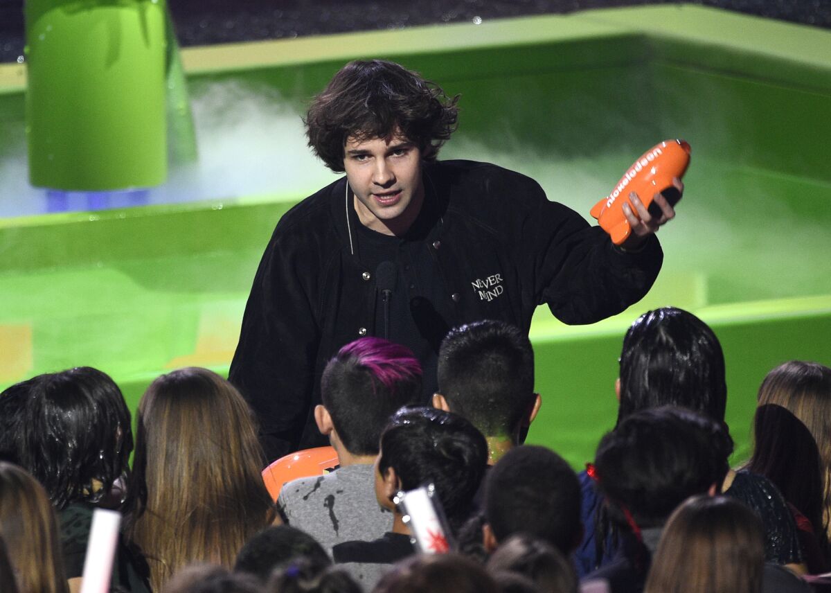 David Dobrik in a crowd holding an orange Nickelodeon blimp trophy