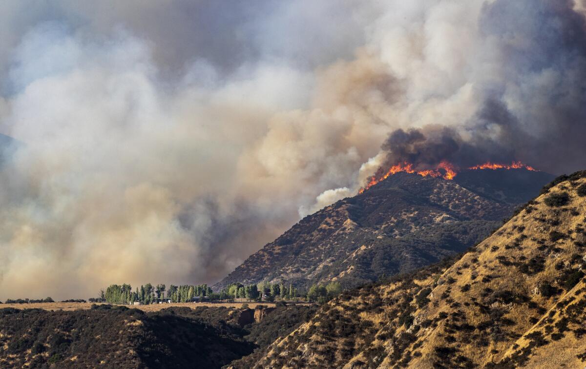 Flames scorch a ridge overlooking homes as the Apple fire burns Sunday in Cherry Valley.