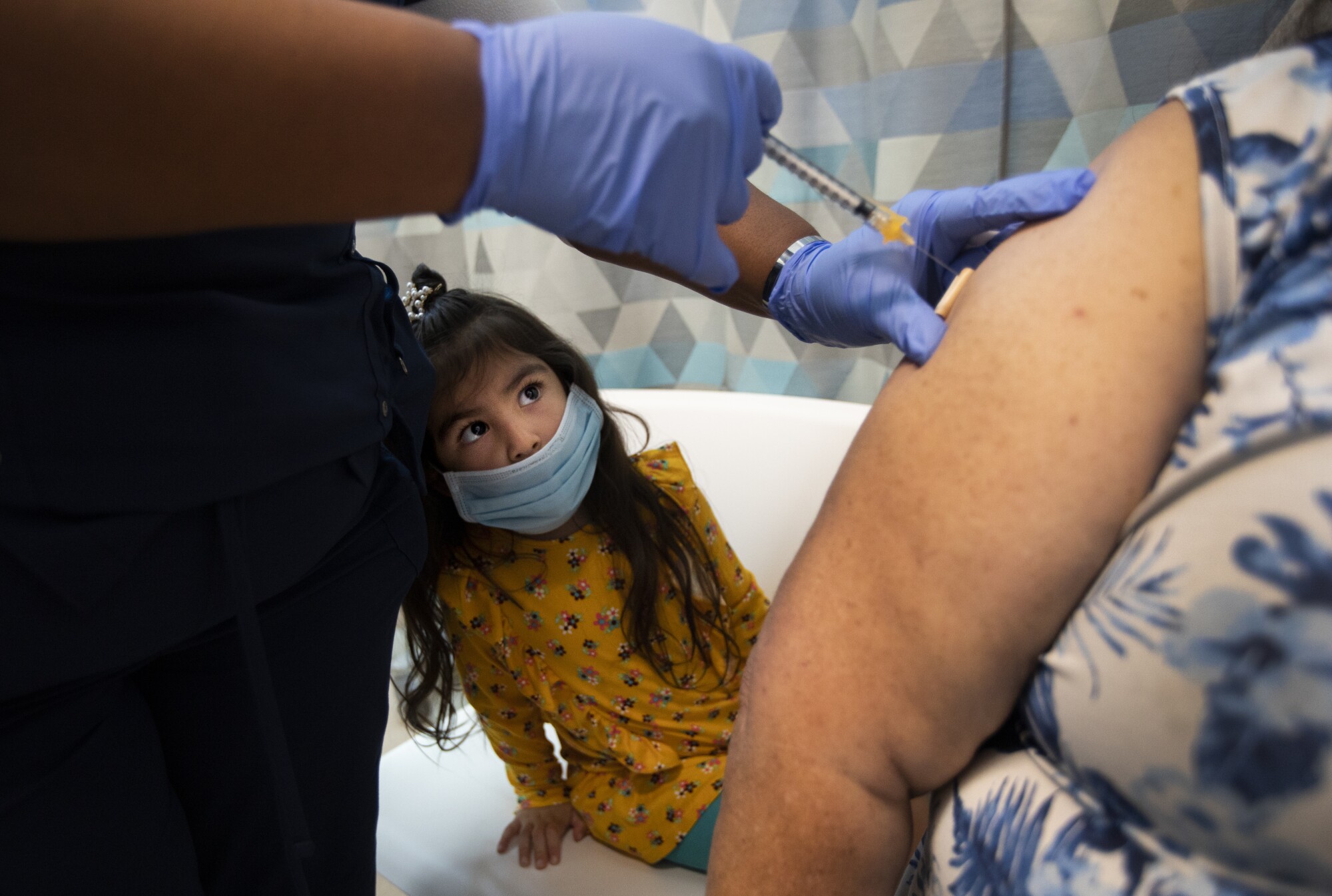 A child watches a nurse administer a vaccine.