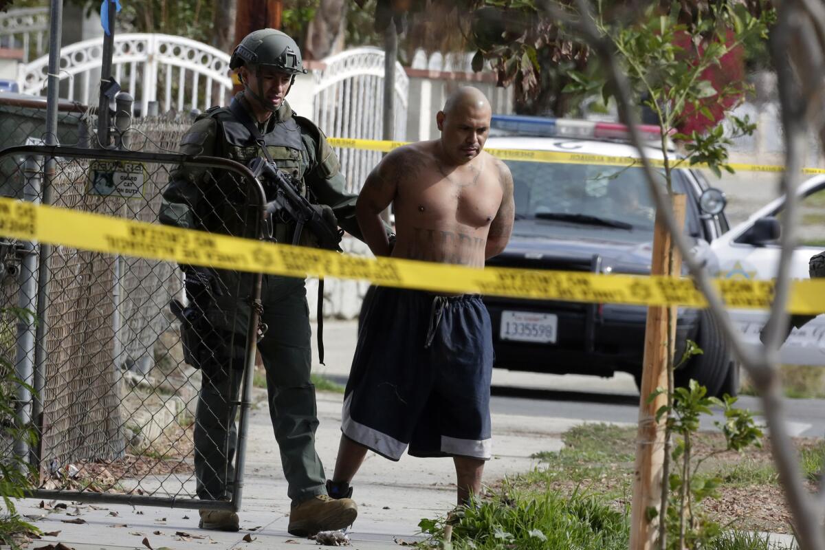 A Los Angeles County SWAT officer escorts out a man after a standoff at a Pico Rivera home Friday morning.