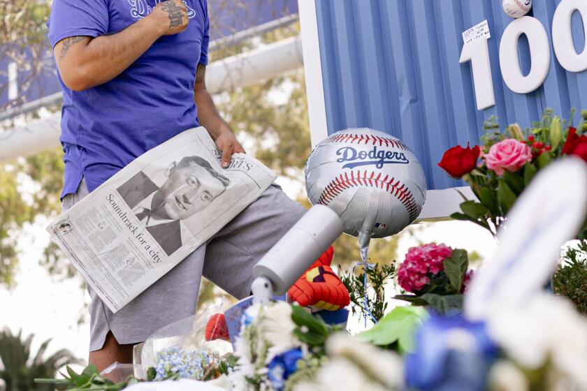 Los Angeles, CA - August 03: JD Redhouse says a prayer at the growing memorial for longtime beloved baseball announcer, Vin Scully, outside Dodger's Stadium, on Wednesday, Aug. 3, 2022 in Los Alamos, CA. (Wesley Lapointe / Los Angeles Times)