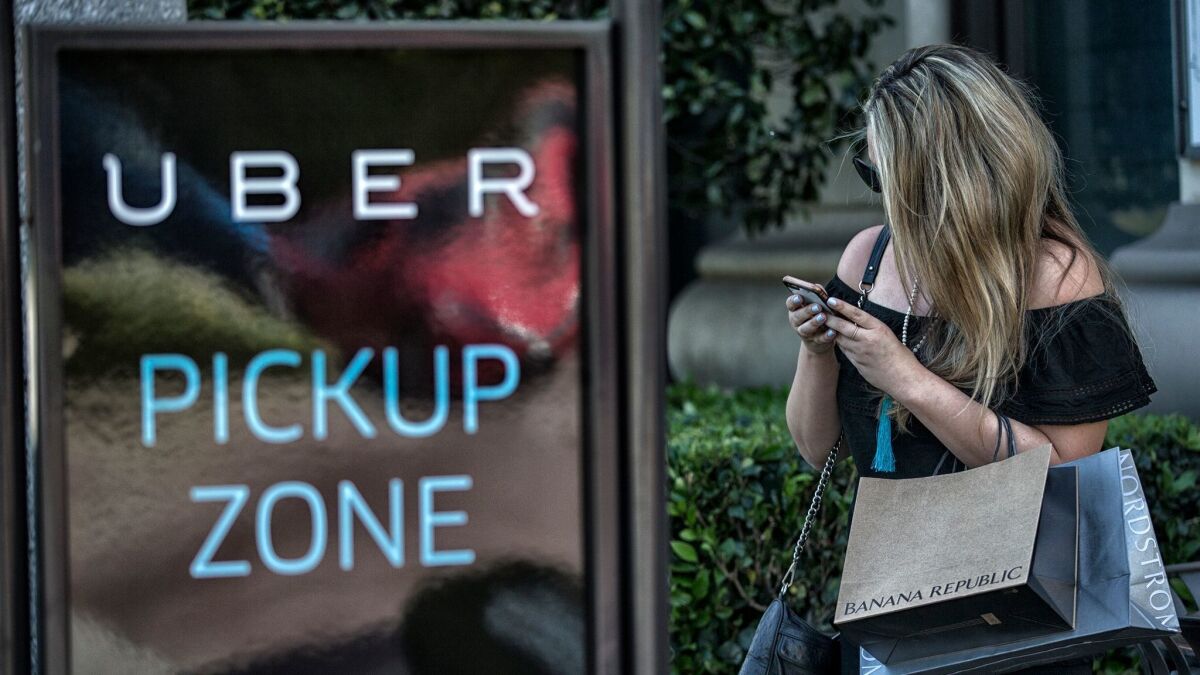 A shopper earlier this month at the Grove shopping mall waits for a ride from an Uber driver.