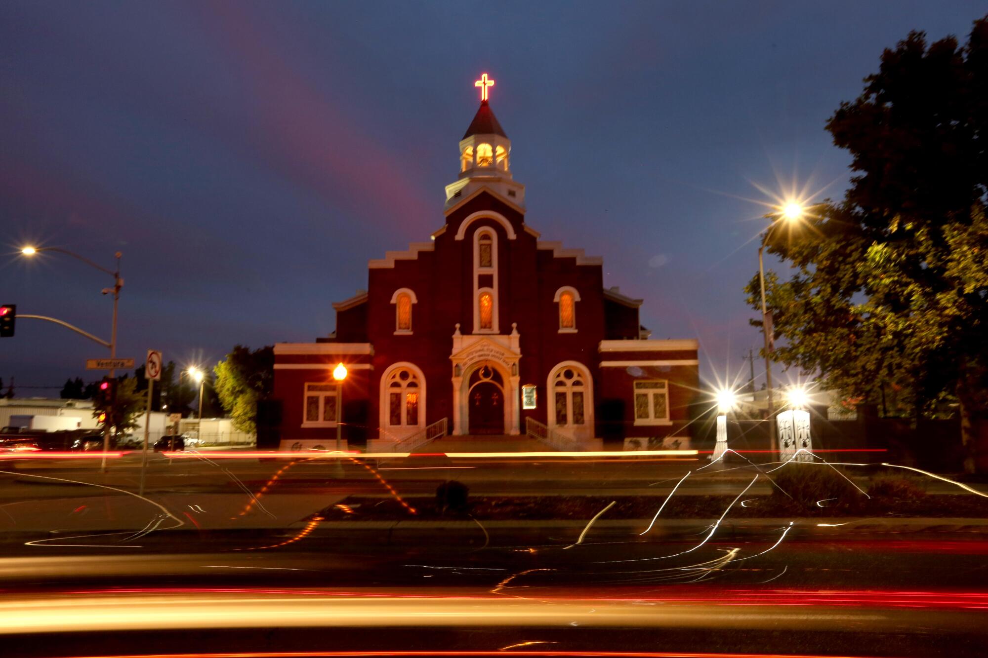 A church building at night with streaks from car lights in the foreground