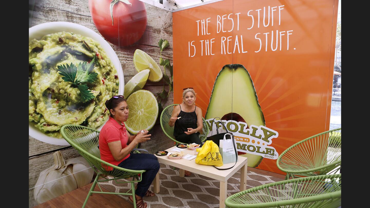 Sisters Dina Sanchez, left, and Edith Sanchez, right, enjoy free guacamole, chips and a taco at the Wholly Guacamole Guac Stop pop up restaurant at the Americana at Brand in Glendale on Friday, July 28, 2017.